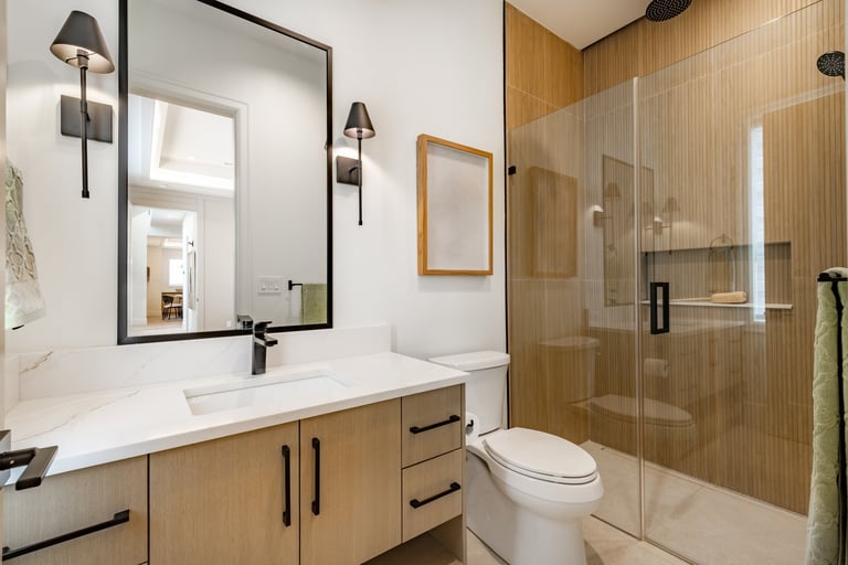 Newly built home bathroom interior primary or master bath with glass wall shower white marble granite floors and countertops large windows with blinds covering free standing bathtub sinks black fixtures bright spacious modern