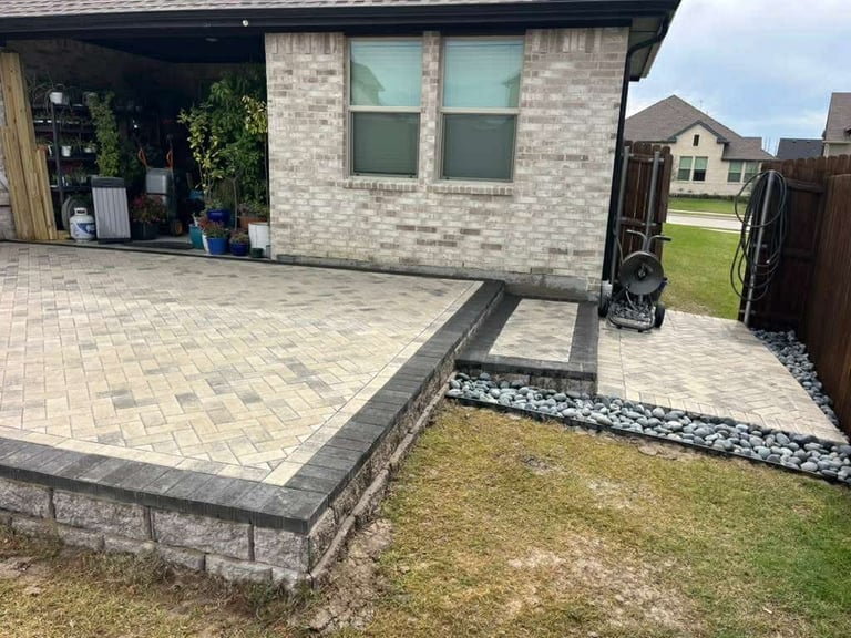 Modern brick house with newly paved patio featuring geometric stone border and landscaping with white gravel and grass